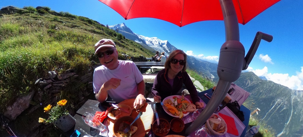 Two hikers enjoying lunch under a red umbrella above Chamonix, France